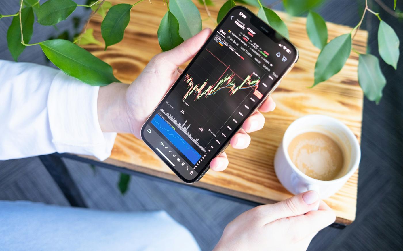 a person holding a cell phone in their hand by TabTrader.com courtesy of Unsplash.