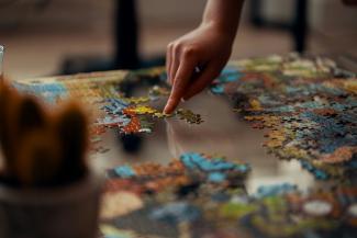 person holding jigsaw puzzle piece by Ross Sneddon courtesy of Unsplash.